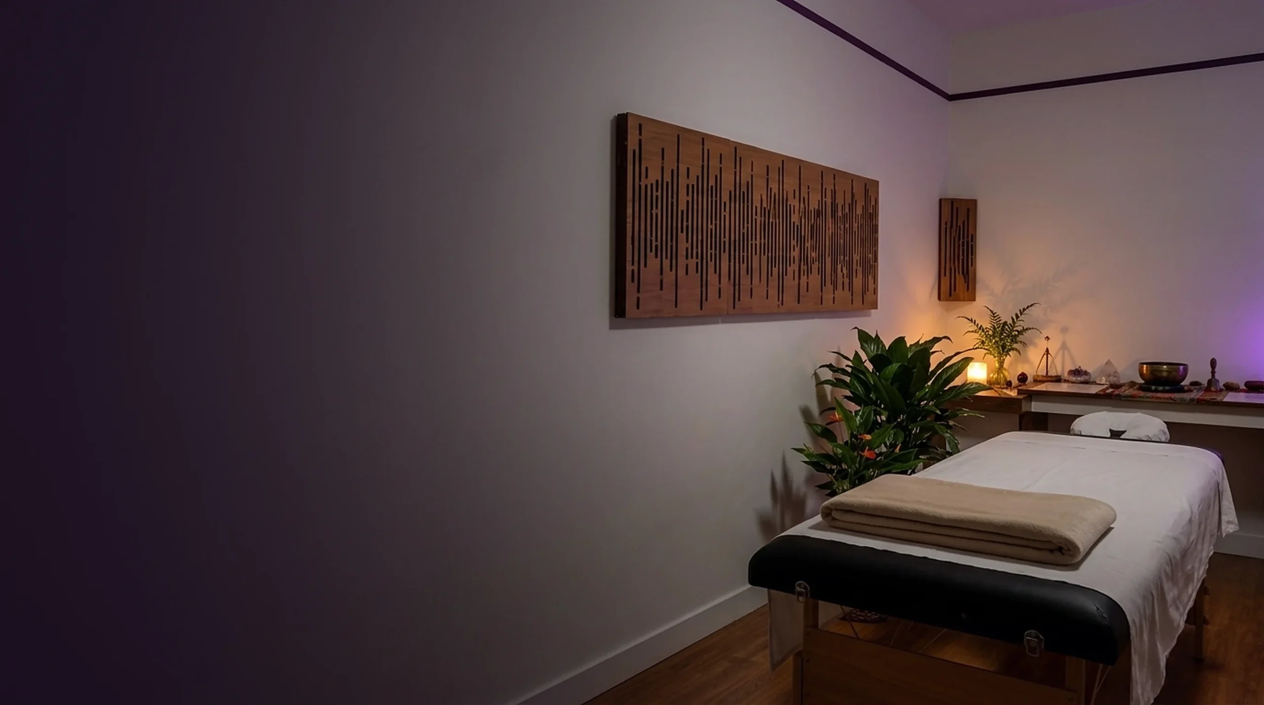 Ambiente de atendimento em penumbra, com maca e luz violeta suave.